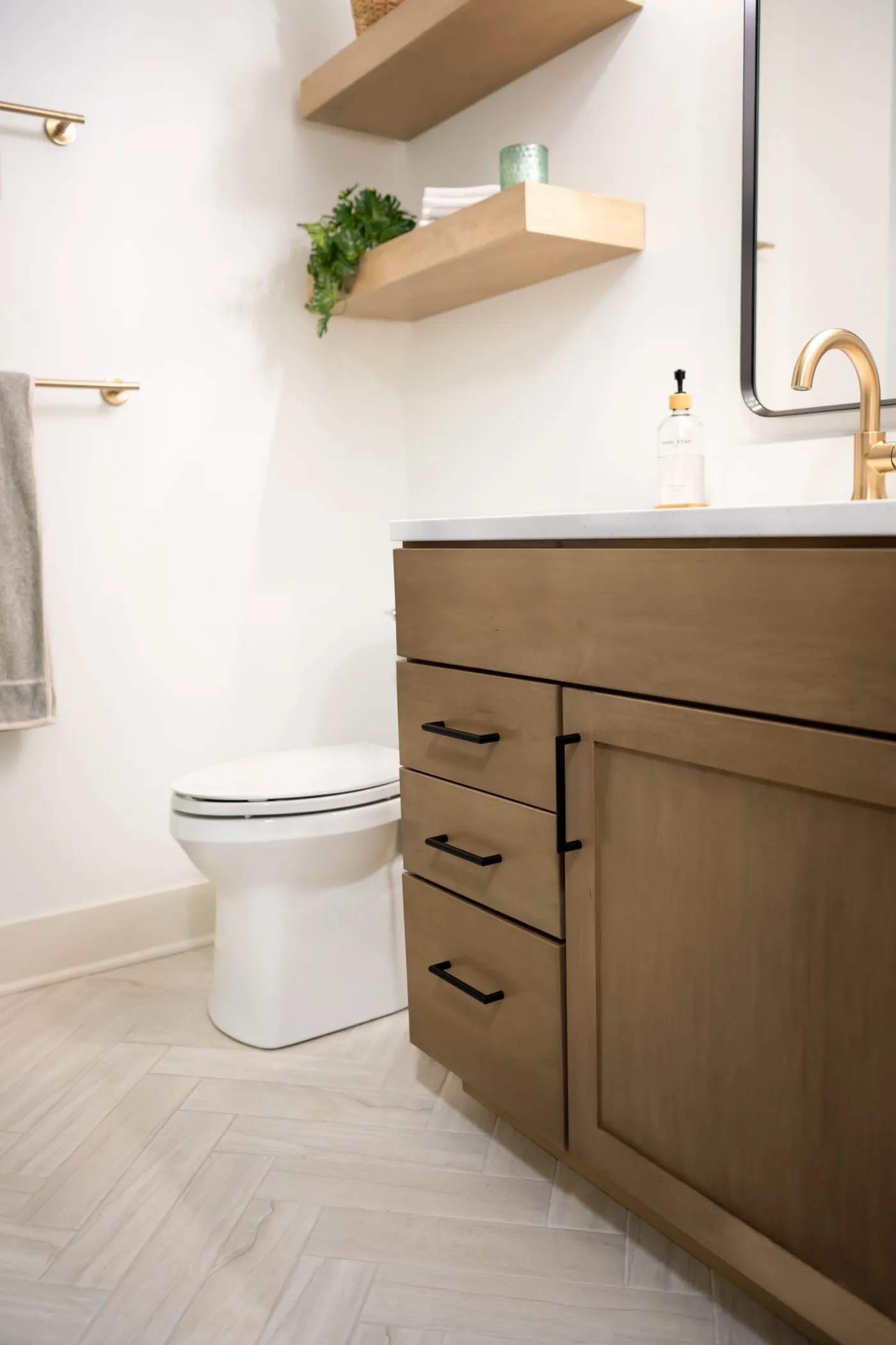 Remodeled Salem Township bathroom with a wood vanity, black hardware and floating shelves