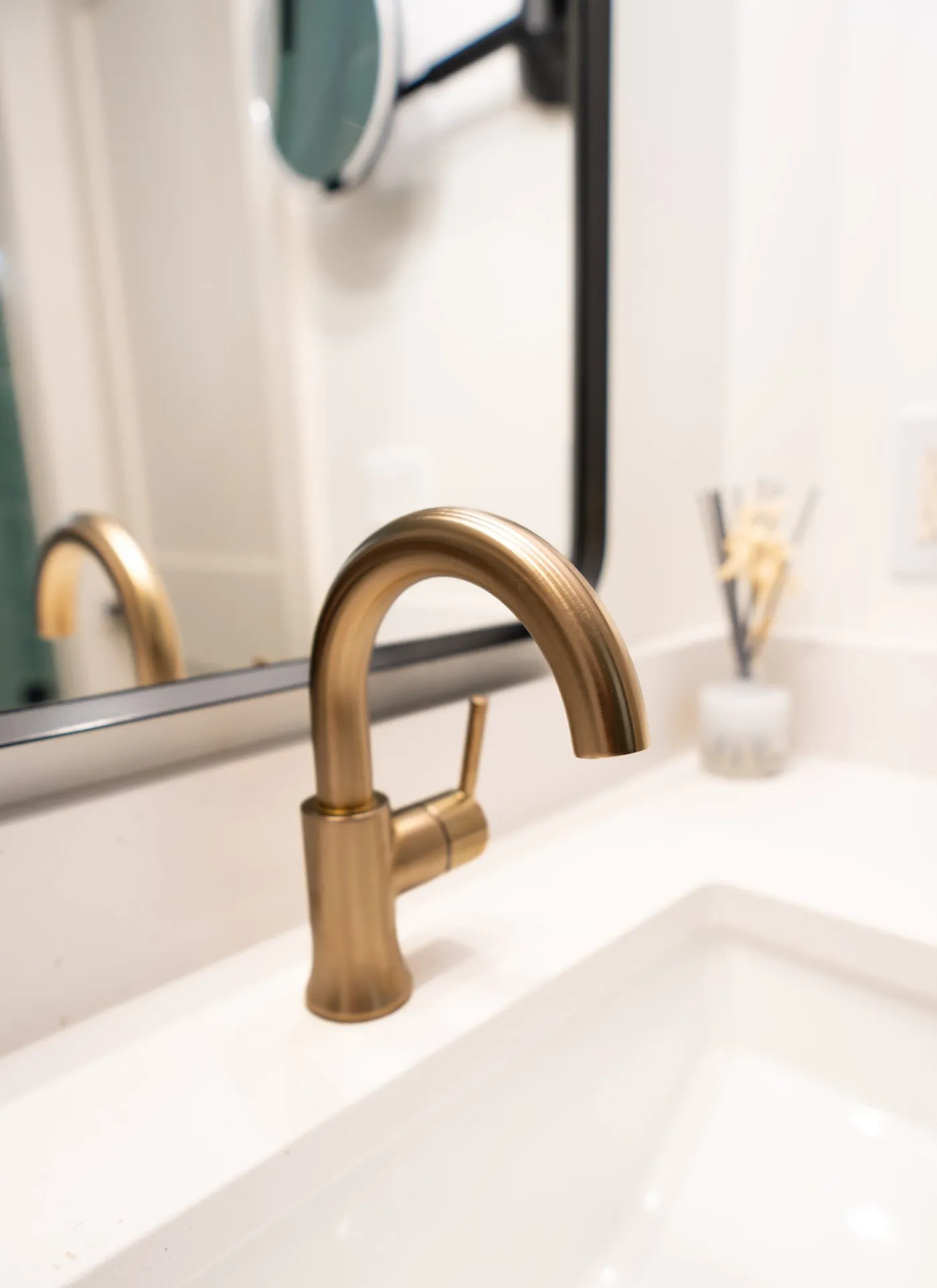 Brushed brass faucet on a quartz vanity top with an undermount sink