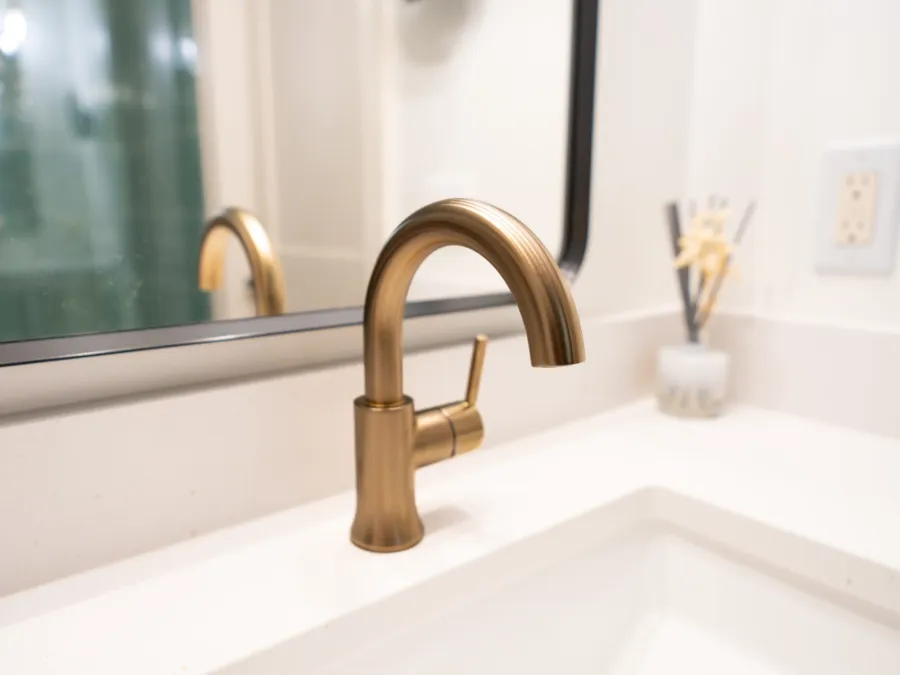 Brushed brass faucet on a quartz vanity top with an undermount sink