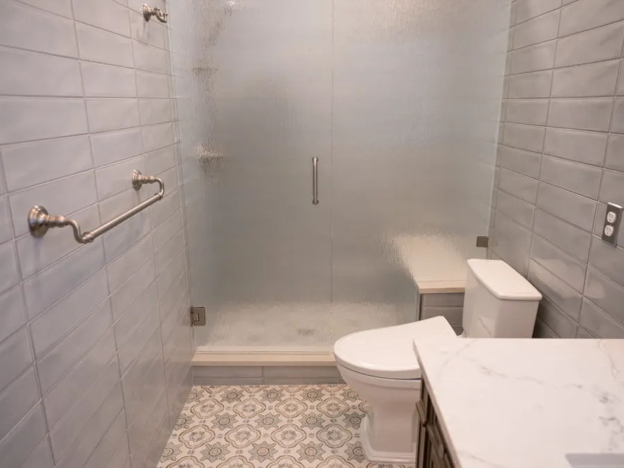 Walk-in tiled shower with a frosted glass door and low threshold