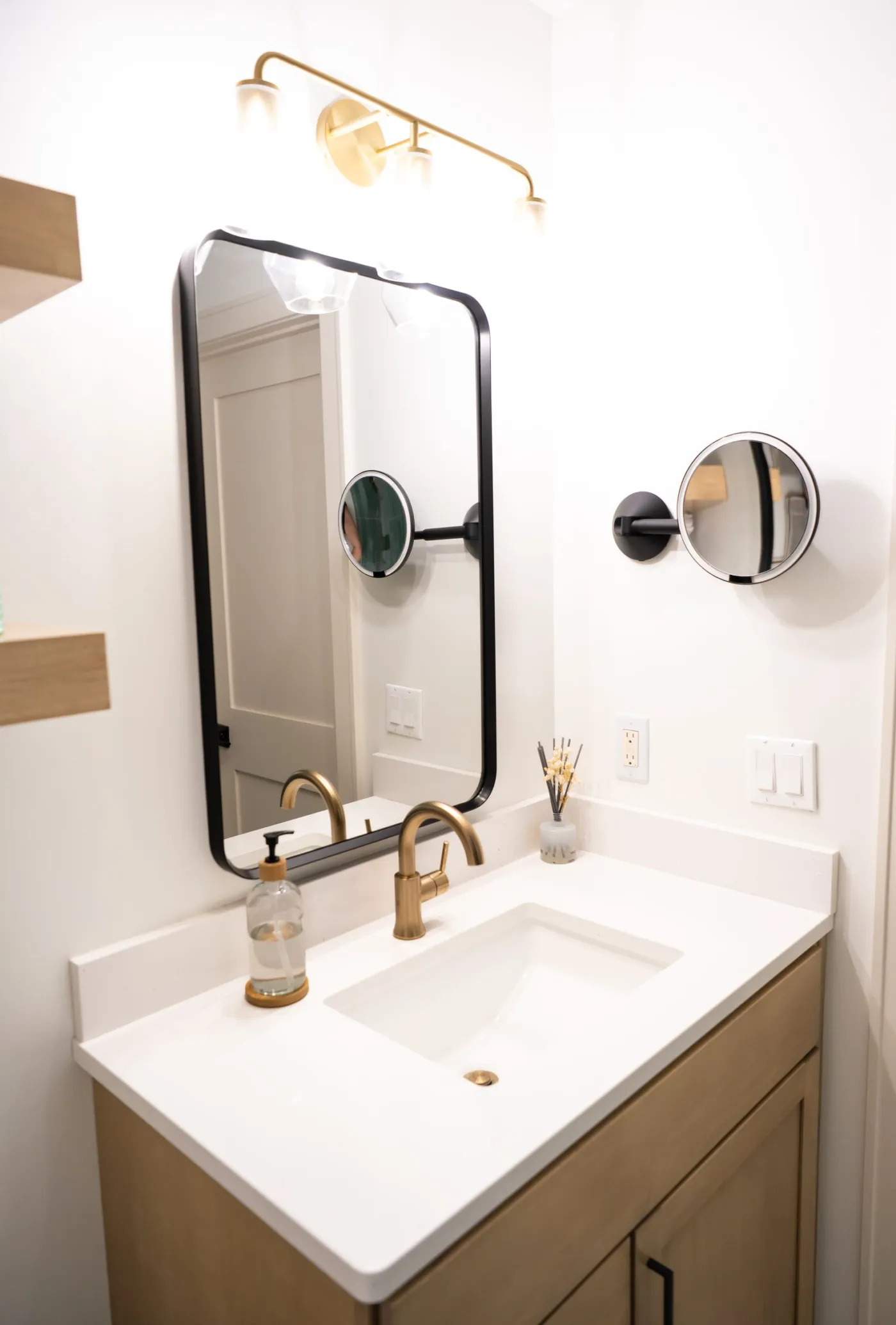 White oak vanity with a quartz top and arched black mirror