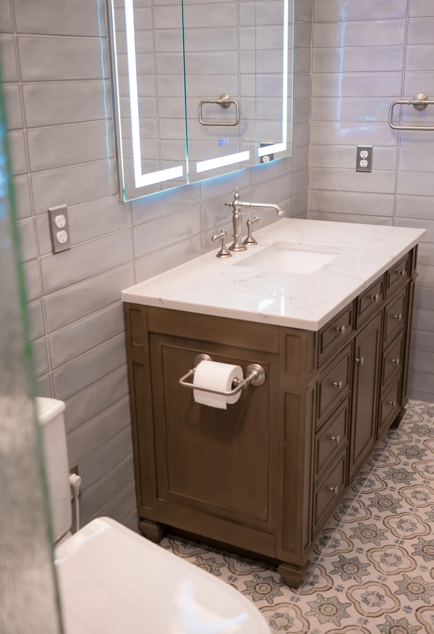 Dark wood vanity with a quartz top and patterned floor tile